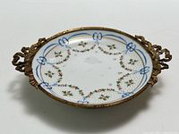Top view showing painted floral garlands, blue bows, bronze rim and handles
