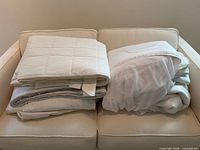 Stacked white quilted mattress covers on sofa