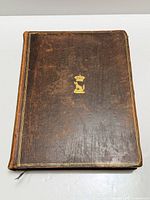 Front cover of leather bound book with gilt crest