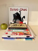 Stack of seven children’s books with an apple for scale; visible titles