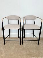 Front view of both stools showing overall design, upholstery, frame, and armrests