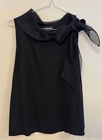 Front view of black sleeveless top showing sheer bow neckline