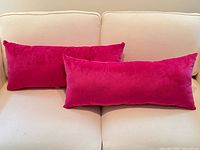 Two fuchsia chenille pillows on cream sofa