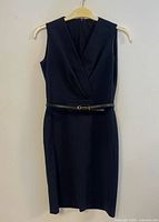 Full front view of navy sheath dress with belt on hanger