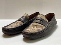 Oblique view of both loafers showing monogram canvas fronts and leather sides