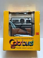 Front view of Kodak Colorburst 100 camera inside yellow retail box