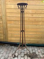 full view of tall wrought iron plant stand against fence