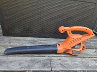 Left side view of orange Black & Decker corded leaf blower showing nozzle and housing wear