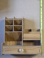 Front view showing drawer with crystal knob, upper compartment, and six vertical slots