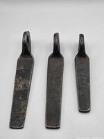 Front view of three pitons showing blade lengths and eyes