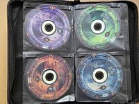Binder page showing four Stargate SG-1 DVDs with purple, green, bronze and blue labels