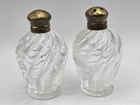 Front view of both swirl glass shakers with brass lids