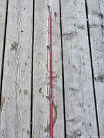 Full length view of red fiberglass rod on wooden deck