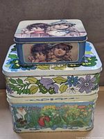 Stacked view of all three tins showing relative sizes and designs