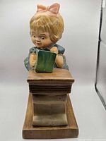 Front view of ceramic girl figurine at desk