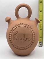 Front view of terracotta jug with Cuba inscription and ruler for height reference