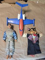 Group shot of action figure, toy jet and hand puppet
