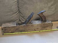 Side view of complete wooden jointer plane with measuring tape indicating about 18in length