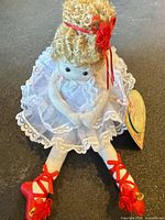 Full view of seated doll showing lace dress and red shoes