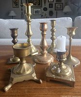 Group shot of all seven brass candlesticks on tabletop