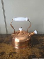 Full view of copper tea kettle showing ceramic handle, lid knob and spout cap
