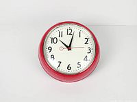 Front view of red wall clock showing dial and casing