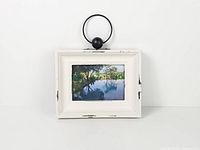 Full view of distressed white picture frame with black metal ring hanger