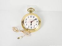 Full view of Spartus pocket watch style reverse wall clock with power cord