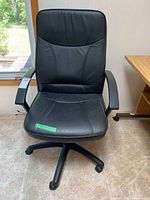 Front view of black office chair showing upholstery, armrests, and base