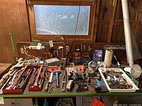 Workbench filled with assorted hand tools, drill bits, fastener trays and work lights