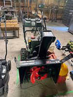 Front view of Troy-Bilt XP 24-inch snowblower with accessories beside it