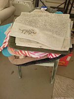 Stack showing assorted towels, mats and blanket on chair