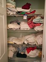 Full closet view showing stacked towels and folded sheets on three wire shelves