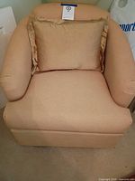 front view of beige fabric armchair with pillow