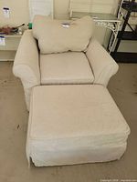 Front view of armchair with ottoman and pillow showing overall style and color