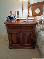 Front view of Ethan Allen nightstand beside bed