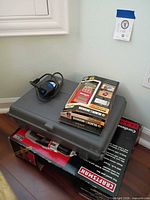 Stack of Fein case, B&D measurer box, Craftsman drill box with corded sander on top