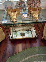 Front view of side table showing glass top, corbels, frame, mirrored shelf
