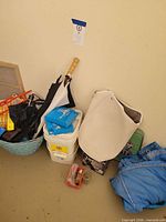Overall view of lot on floor with bucket, umbrellas, tote, blue garment, red hardware box
