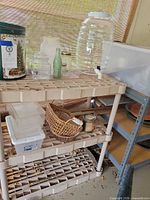 Overall view of plastic shelving with beverage dispenser, bins, jars, tin, basket and bakeware