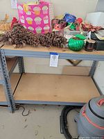 Front view of metal shelving unit with two particle board shelves, assorted personal items on top shelf for scale