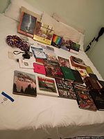 Overall layout of books, puzzles, camera, cables and small items on bed