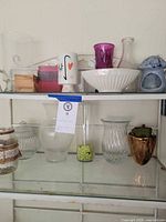 Full shelf showing majority of glass vases, jars, bowl, planter and candle holder