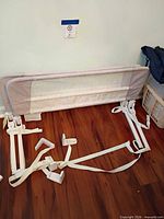 Two Munchkin bed rails laid flat showing mesh panels, metal frames and attachment straps