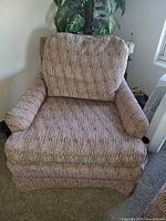 Front view of oversized striped armchair showing upholstery pattern, rolled arms, skirted base
