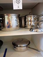 Shelf with stockpot, stacked saucepans, sauté pan and lids