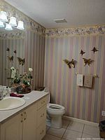 Bathroom overview showing decorative butterflies, monogram towels, floral arrangement, vanity tray and bowl