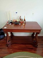 Front view of coffee table showing overall shape, carved legs, lower shelf