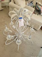 Side view showing overall chandelier form, eight sockets, scroll arms, distressed white finish