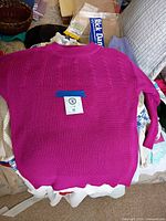 Fuchsia cable-knit crewneck sweater laid flat showing back and texture